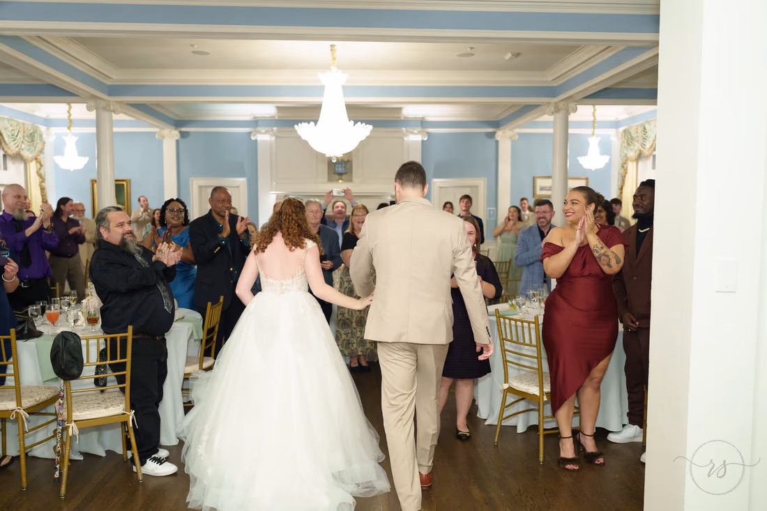 Guests cheer as the bride and groom walk into the ballroom at Pine Lakes Country Club