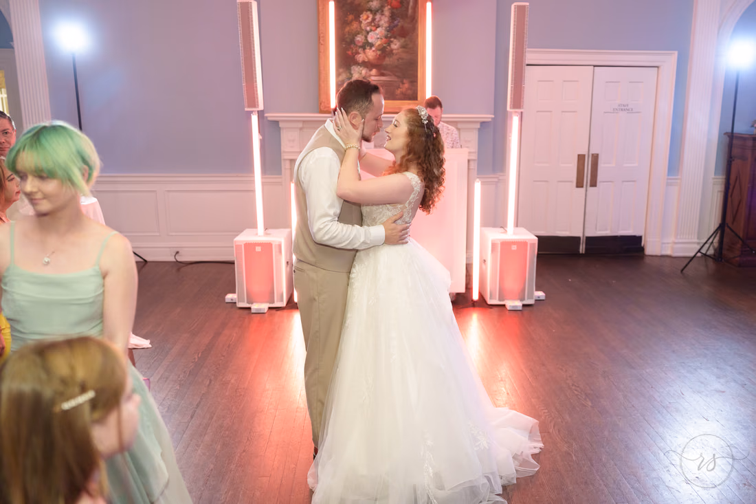 The bride and groom kiss while dancing with friends nearby at Pine Lakes Country Club