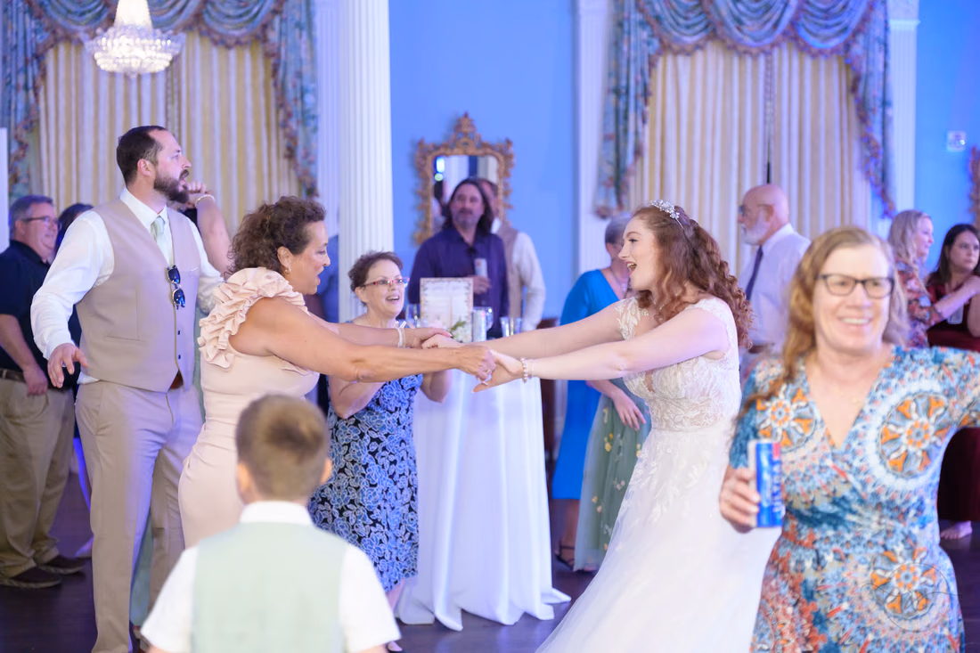 The bride holds hands with guests in a dance circle at Pine Lakes Country Club