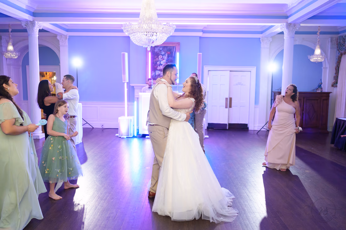 The bride and groom slow dance in the ballroom under purple light at Pine Lakes Country Club