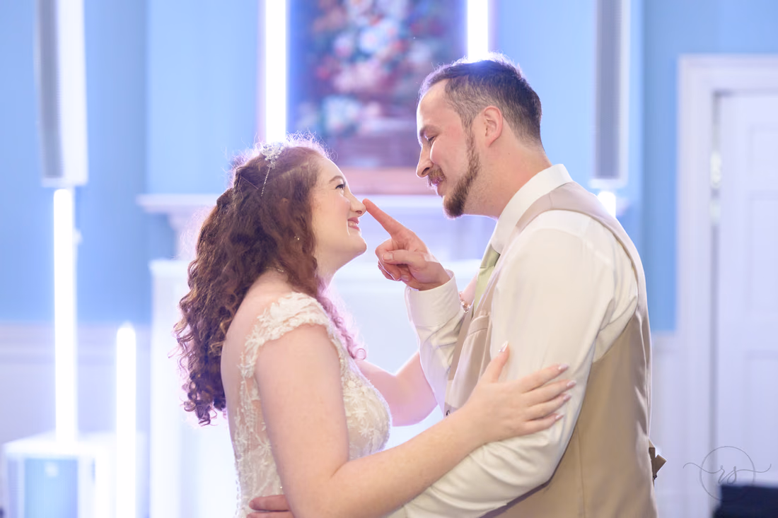 The groom touches the bride's nose as they laugh on the dance floor at Pine Lakes Country Club