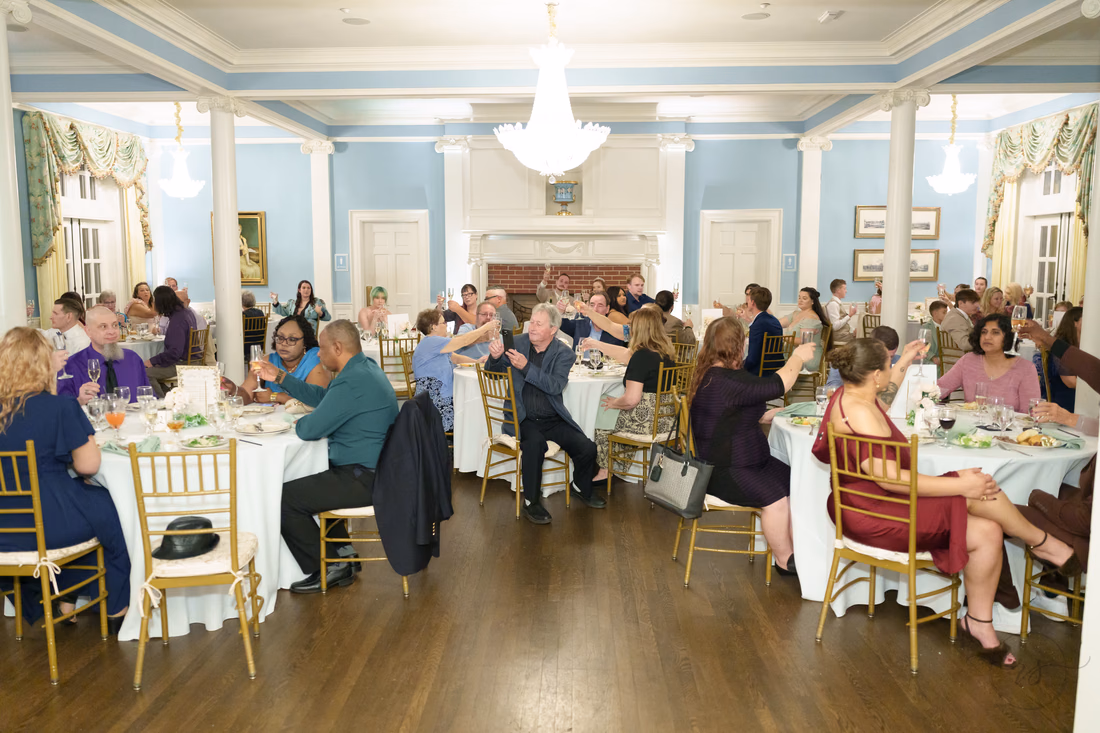 Guests raise their glasses at round tables in the ballroom at Pine Lakes Country Club