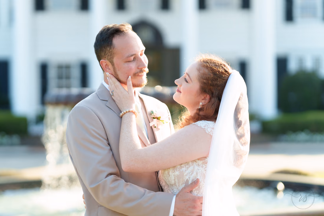 The bride and groom gaze at each other by the fountain at Pine Lakes Country Club
