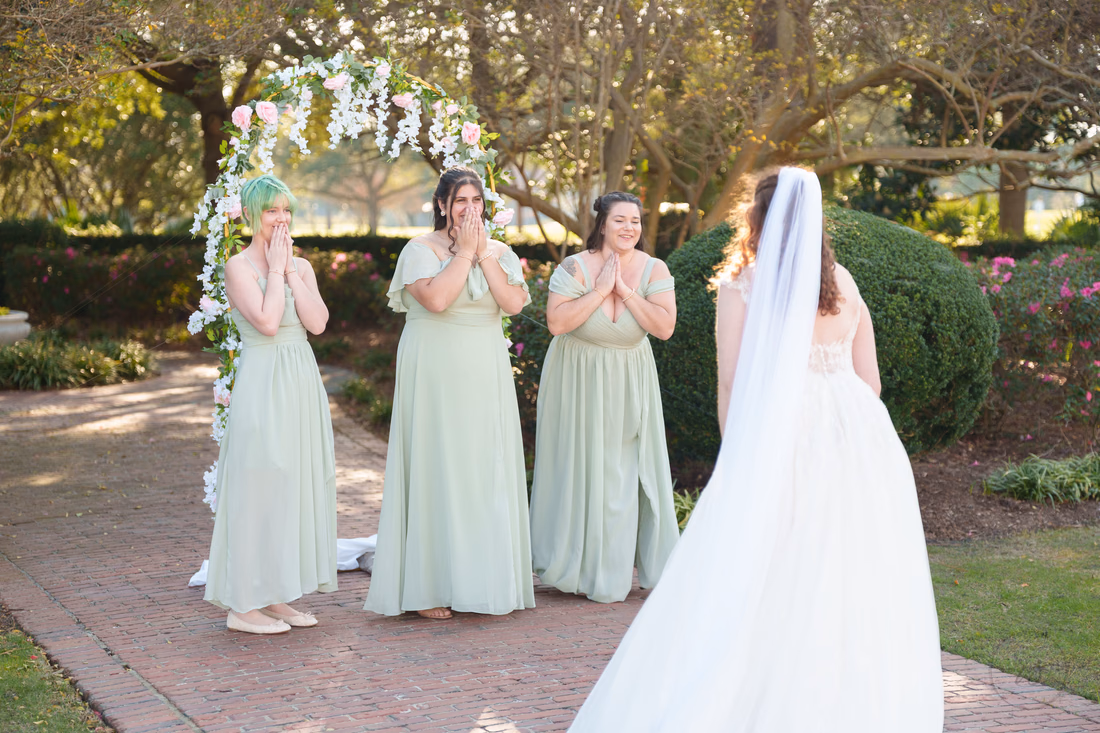Bridesmaids react as they see the bride in her dress in the garden at Pine Lakes Country Club