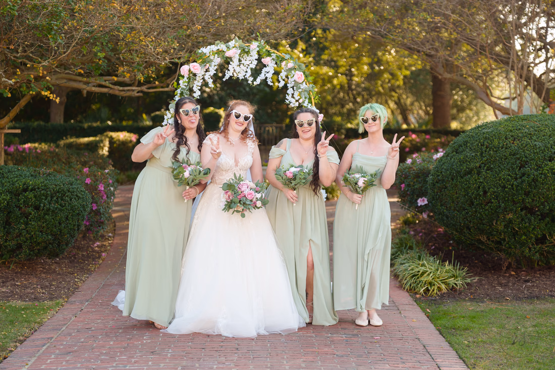 The bride and bridesmaids pose in white novelty sunglasses at Pine Lakes Country Club