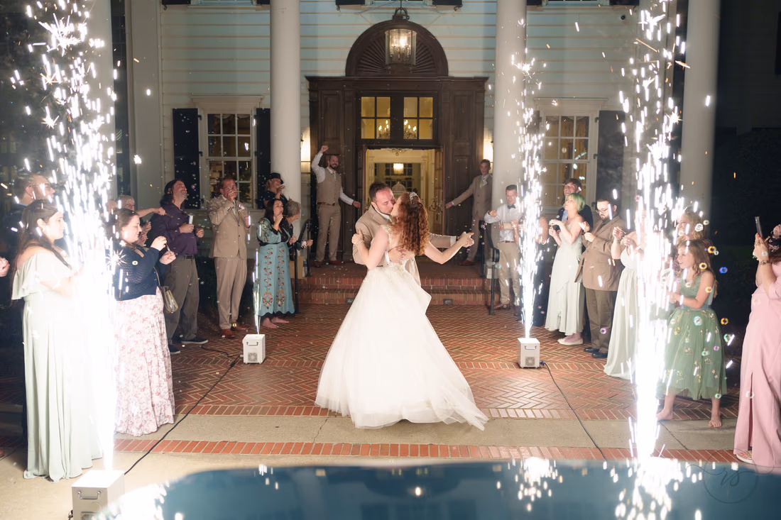The groom dips the bride between sparkler fountains as guests cheer at Pine Lakes Country Club