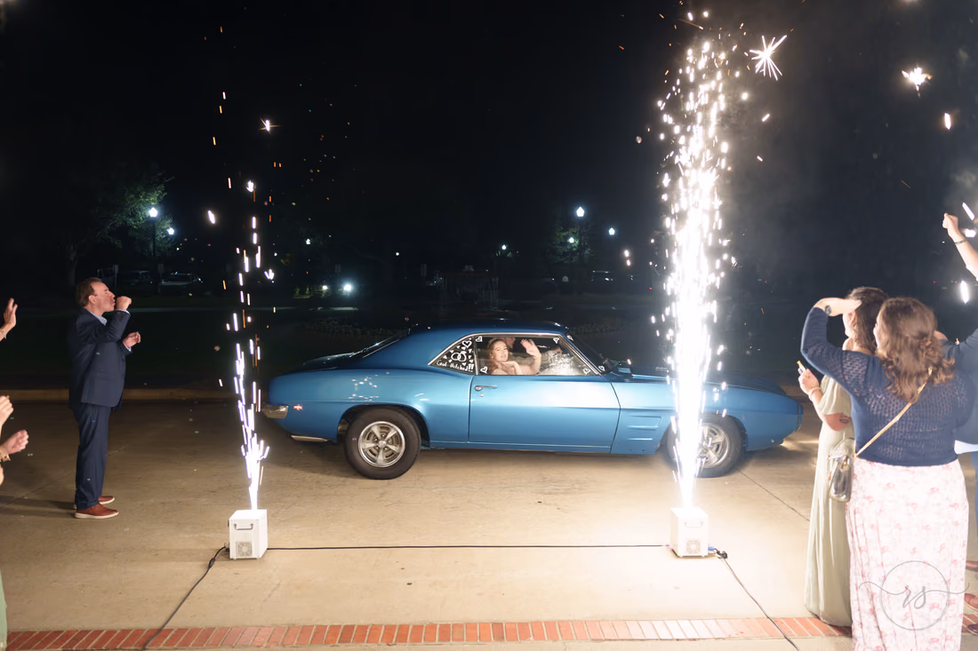 The couple drives off in a blue classic car past the sparklers at Pine Lakes Country Club