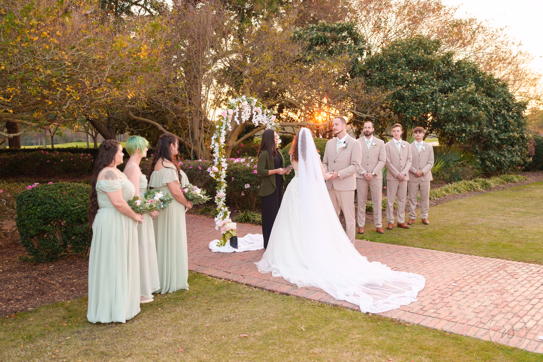 The bride's long train on the brick path during the ceremony at sunset at Pine Lakes Country Club