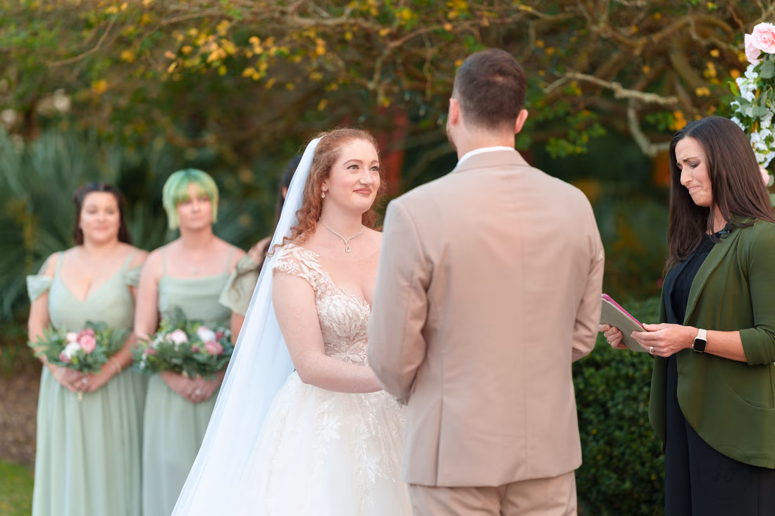 The bride smiles at the groom during the ceremony at Pine Lakes Country Club