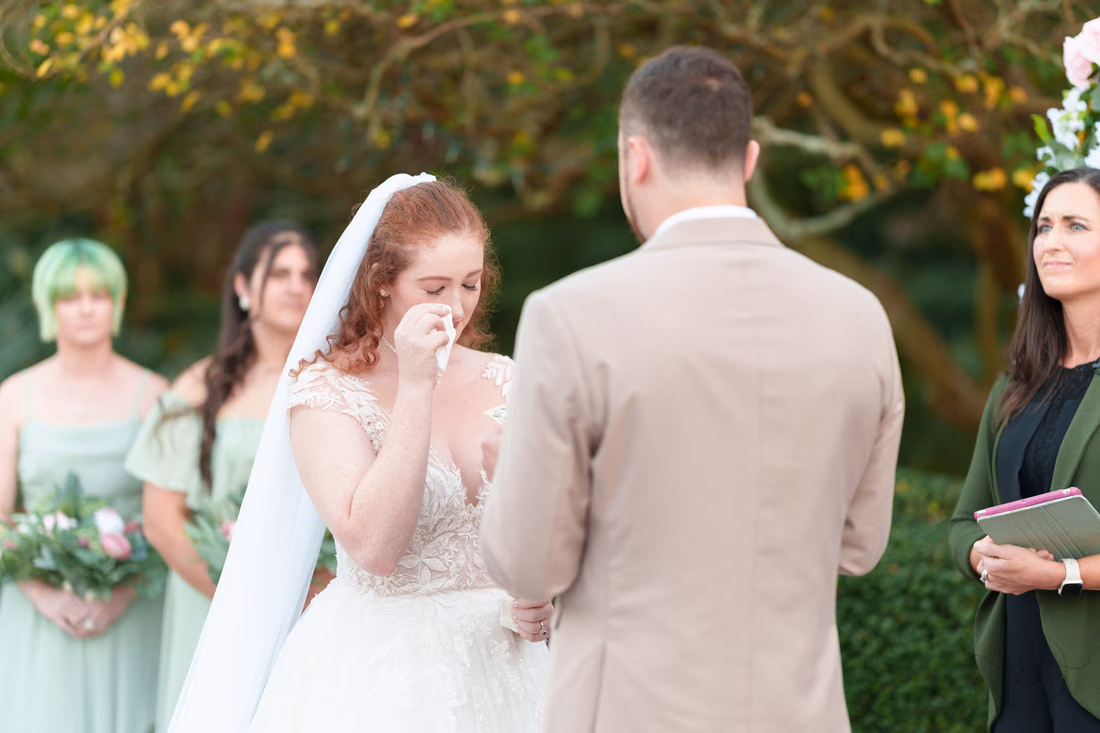 The bride wipes a tear during the vows at Pine Lakes Country Club