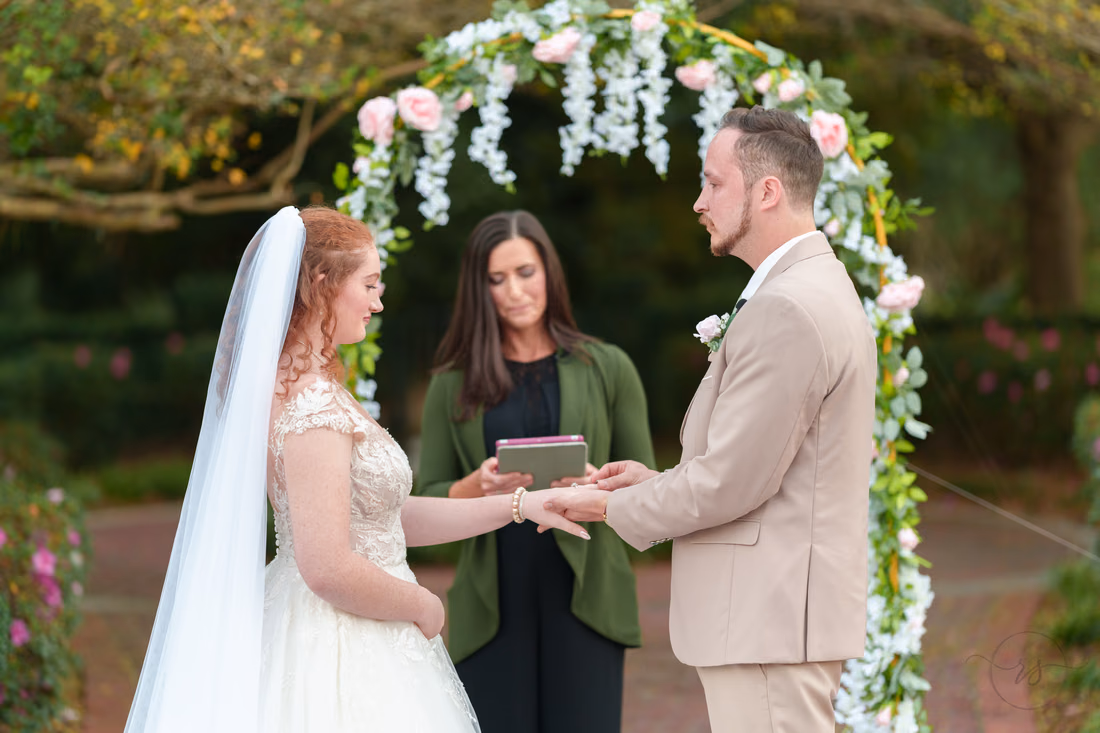 The groom places the ring on the bride's finger at Pine Lakes Country Club