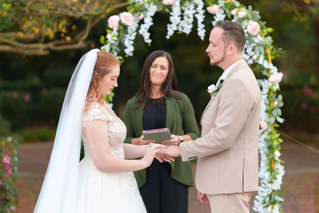 The bride slides the ring onto the groom's finger at Pine Lakes Country Club