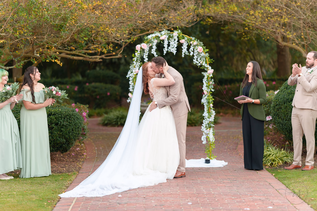 First kiss under the flower arch as guests applaud at Pine Lakes Country Club
