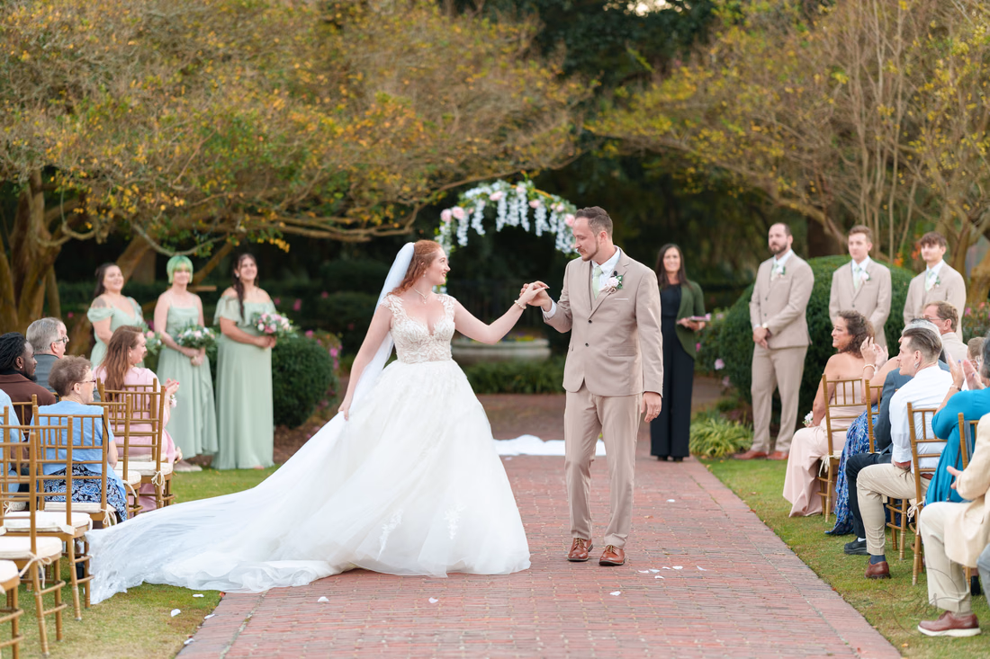 The bride and groom start back up the aisle as guests cheer at Pine Lakes Country Club