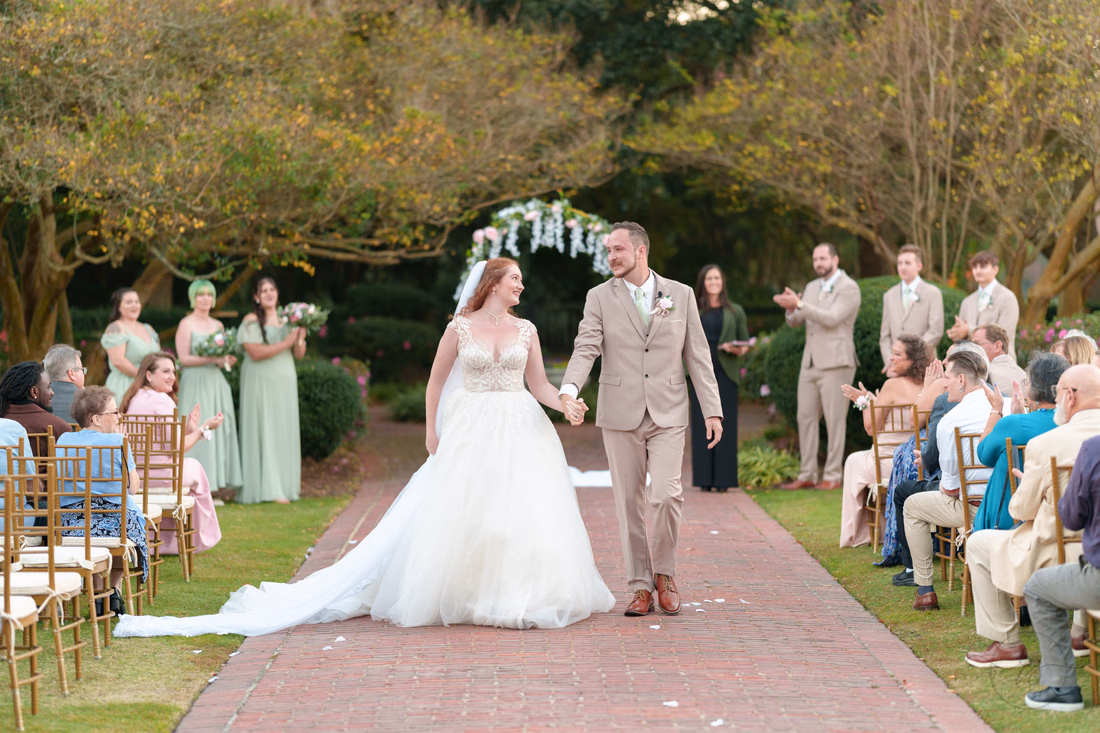The newlyweds walk up the brick aisle hand in hand at Pine Lakes Country Club