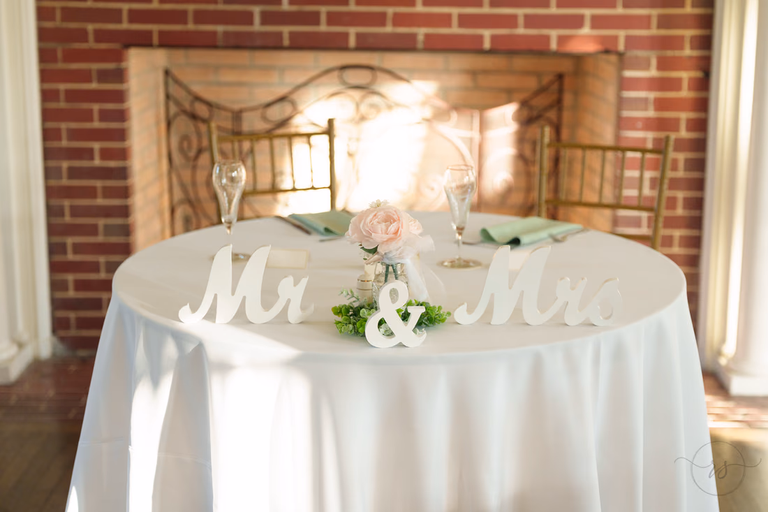 Sweetheart table with a Mr &amp; Mrs sign by the brick fireplace at Pine Lakes Country Club
