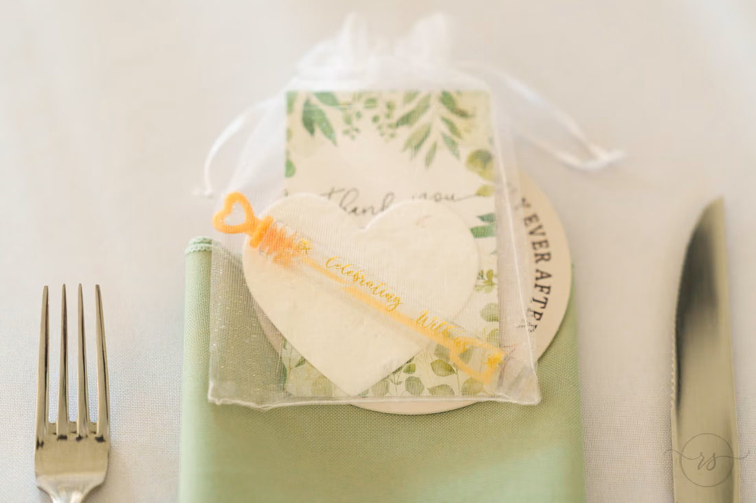 Heart-shaped favor and a gold stir stick on a sage napkin at Pine Lakes Country Club