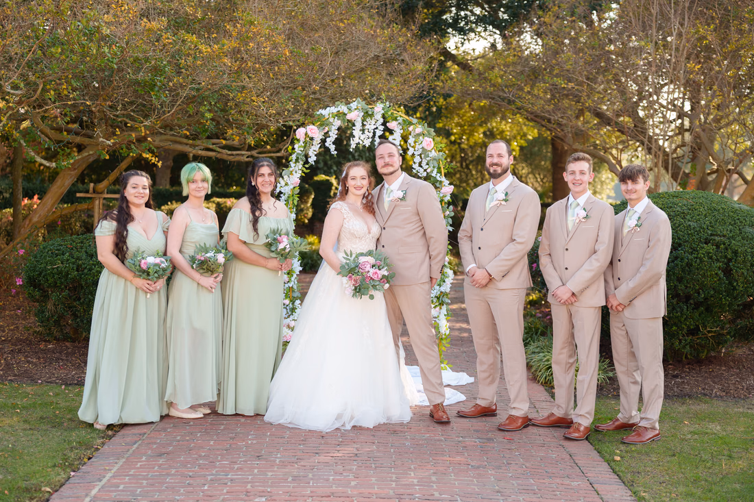 The full wedding party lined up on the garden path at Pine Lakes Country Club