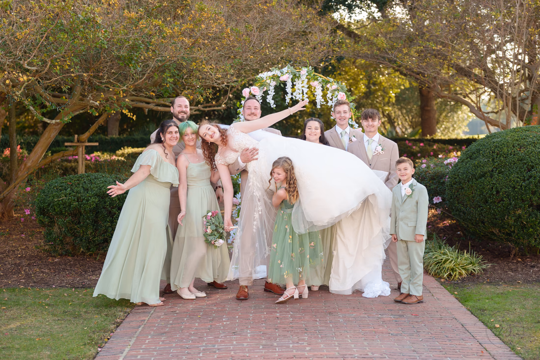 Groomsmen lift the bride as the wedding party laughs at Pine Lakes Country Club