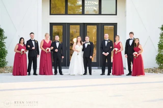 Bridal party posing in front of the white venue doors at The Venue at White Oaks Farm