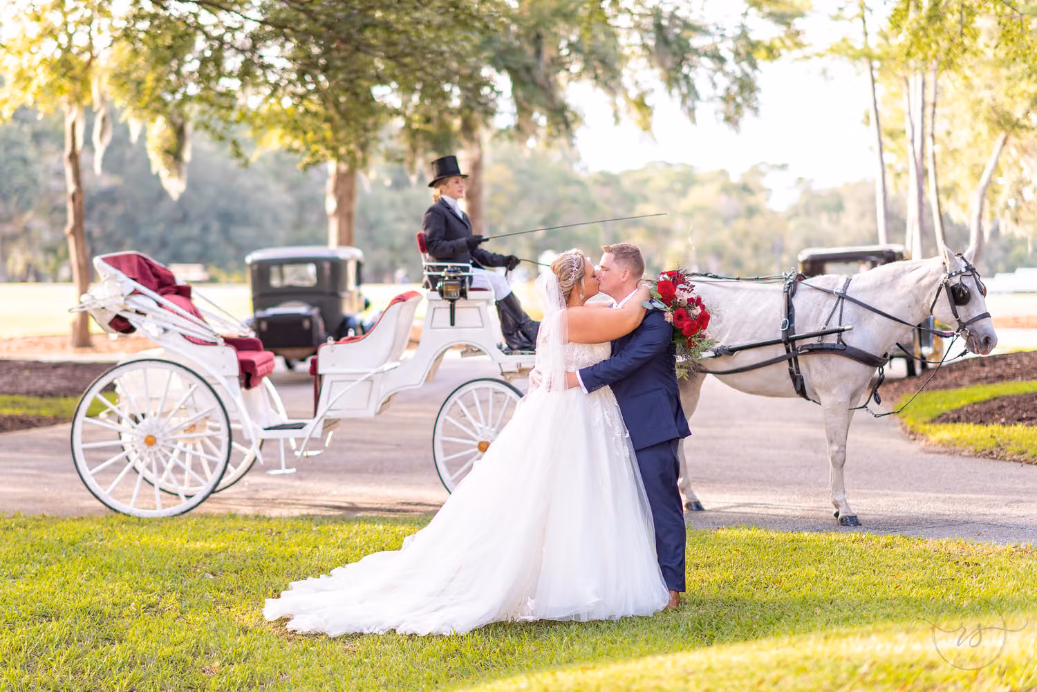 Bride and groom kissing in front of a white horse-drawn carriage at Pawleys Plantation Golf & Country Club