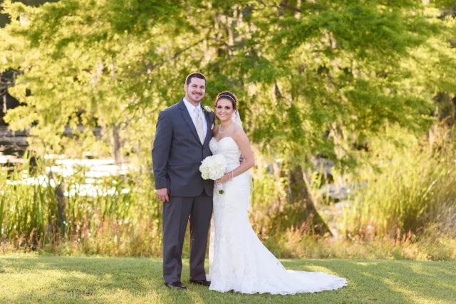 Bride and groom standing on the lawn by the marsh in the evening light at Upper Mill Plantation
