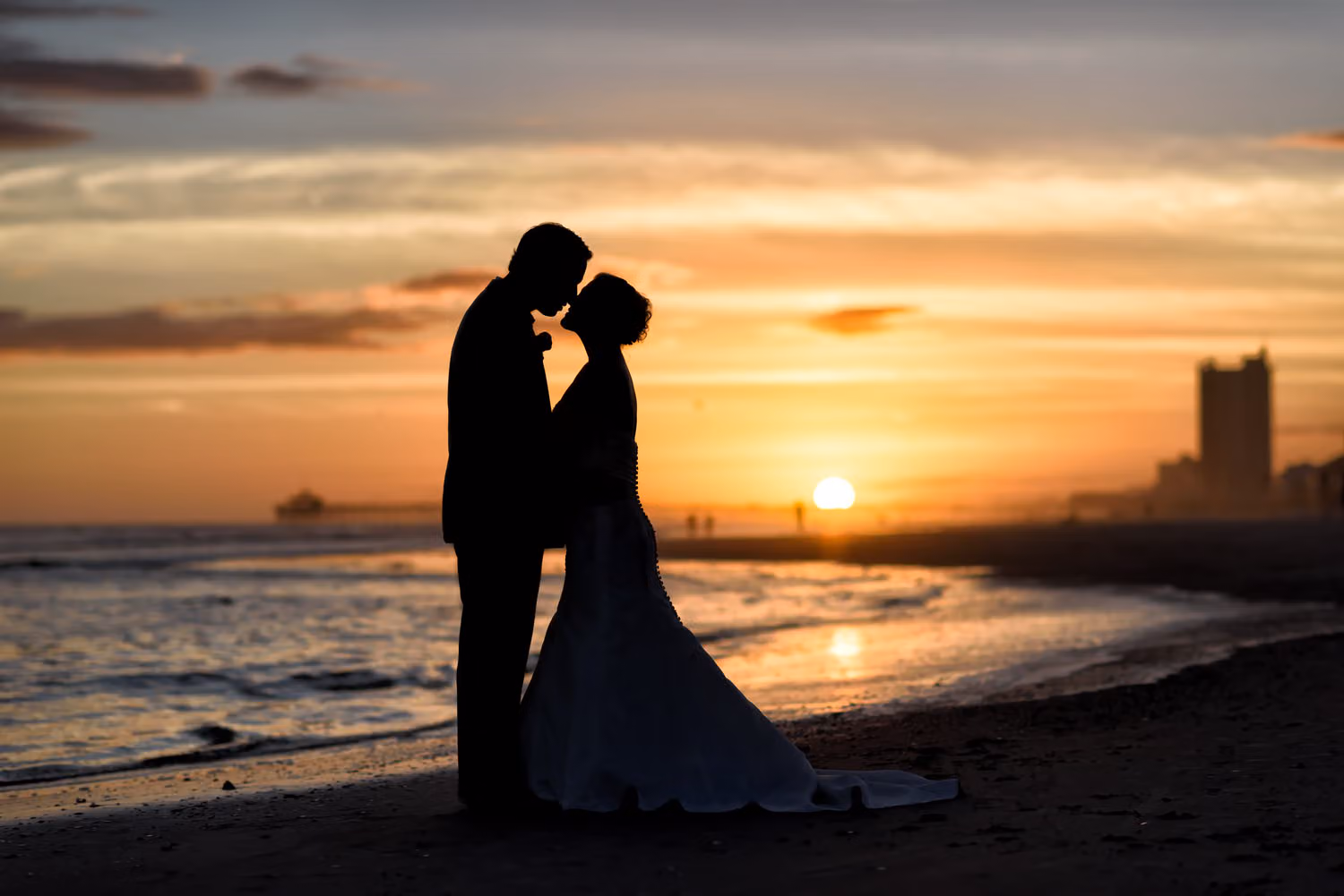 Silhouette of the bride and groom kissing on the beach against an orange sunset sky in North Myrtle Beach