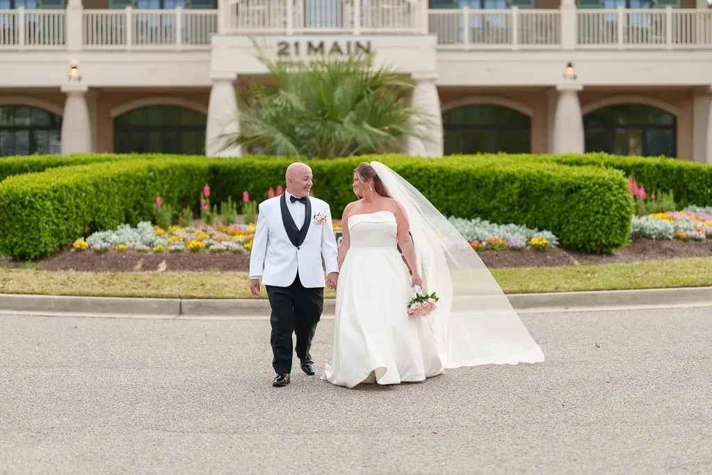 Brooke and her groom walking in front of the 21 Main building on their wedding day