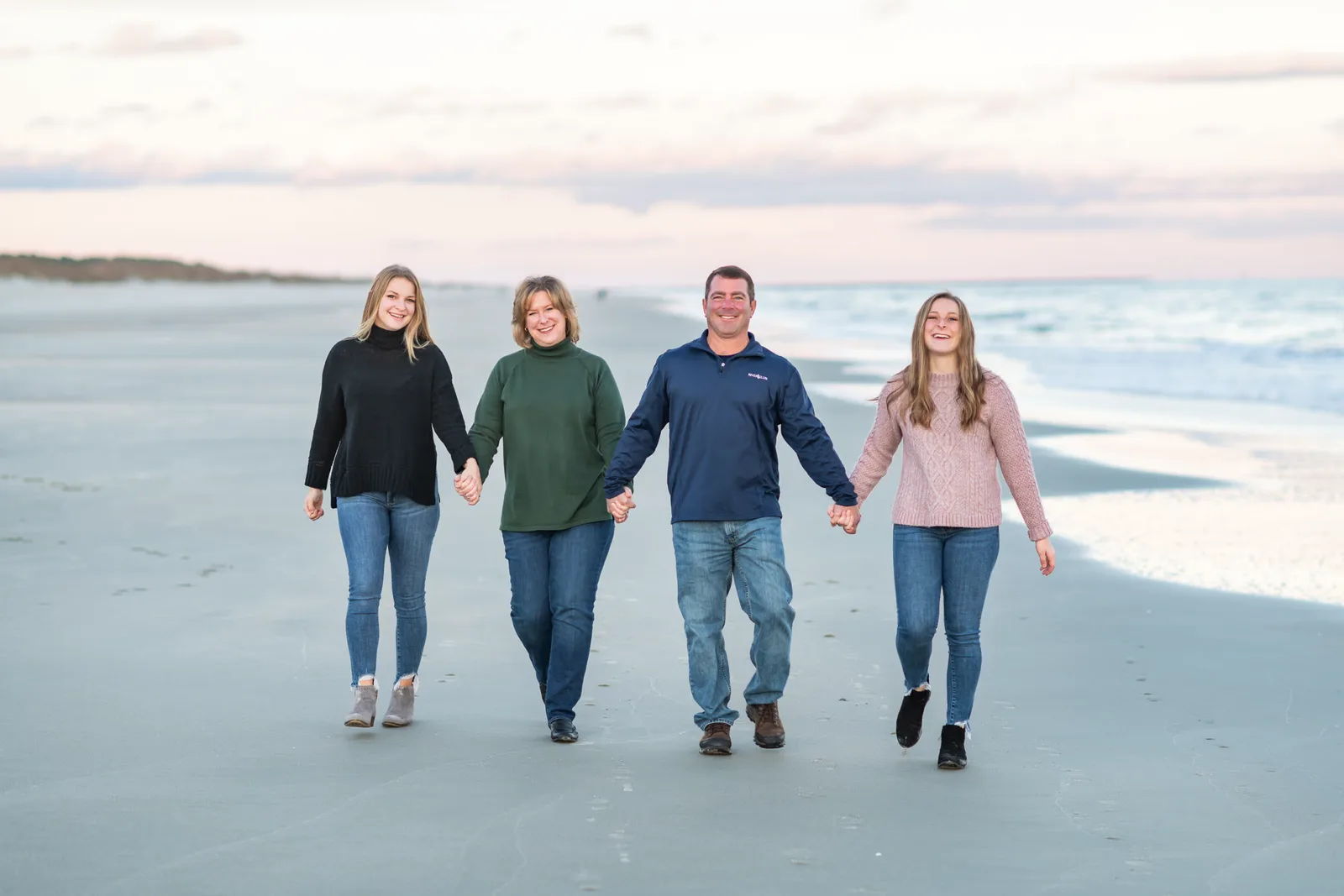 Family holding hands walking down the beach - Huntington Beach State Park