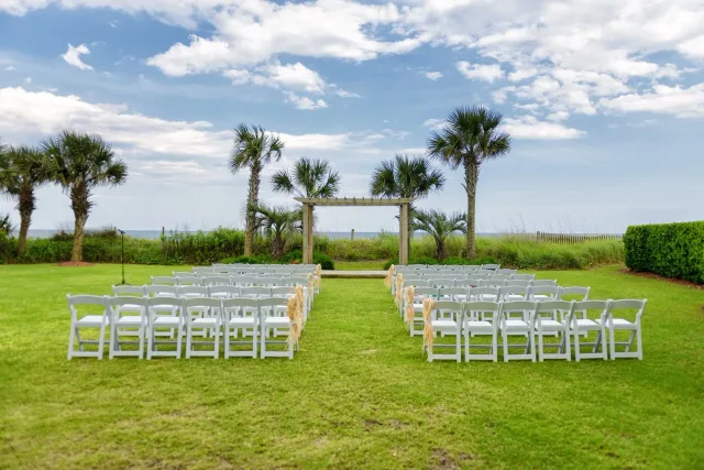 Ceremony chairs and an arbor on the lawn by the palms behind the Hilton in Myrtle Beach
