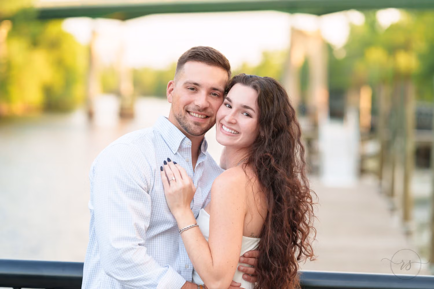 Smiling couple cheek to cheek under the bridge by the river at the Conway Riverwalk