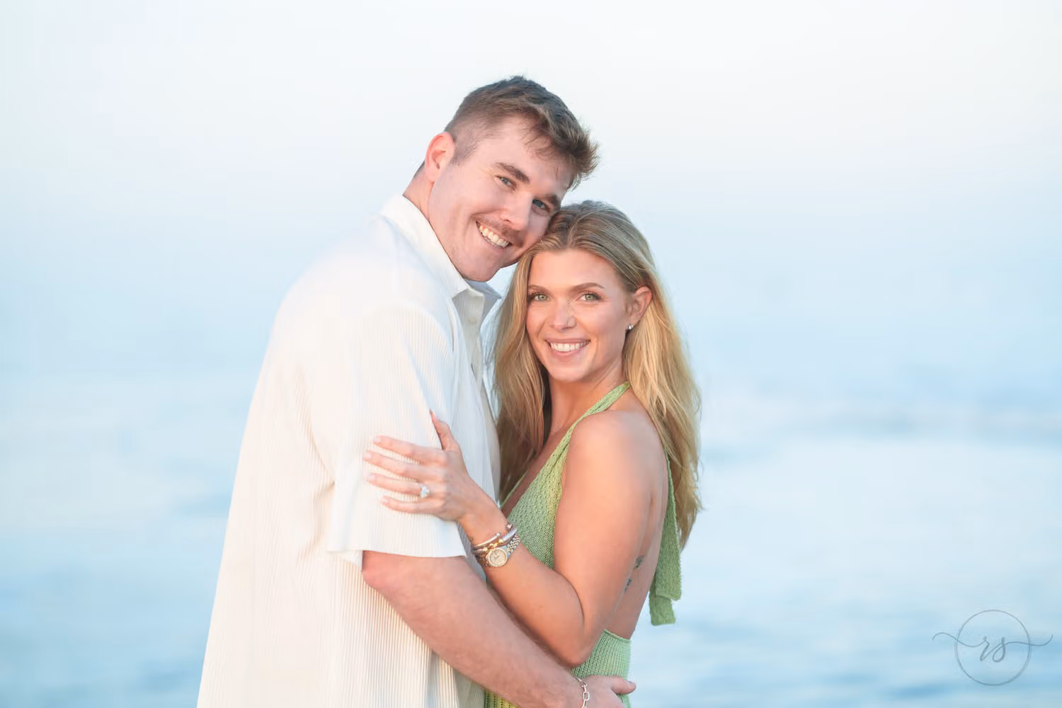 Smiling couple cheek to cheek with the soft blue ocean behind them at Huntington Beach State Park