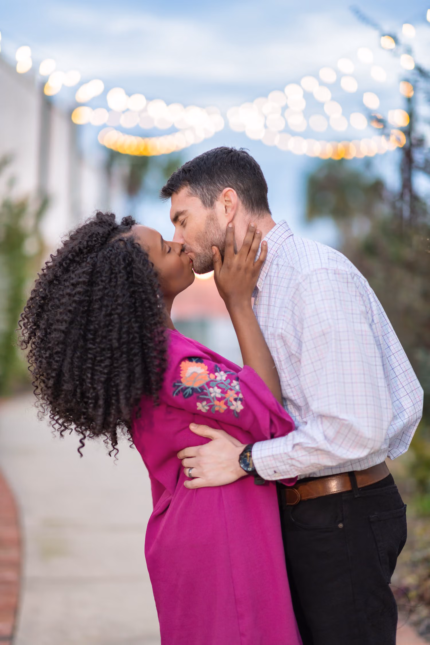 Close view of a couple kissing under strings of hanging lights on the Conway Gardenwalk