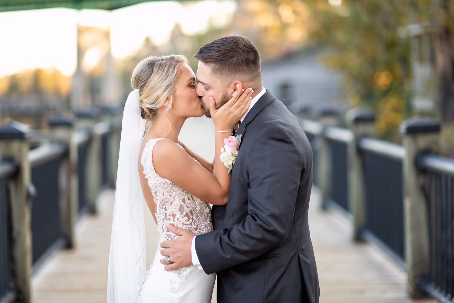Close-up of a bride and groom kissing beside the boardwalk railing in evening light at the Conway Riverwalk