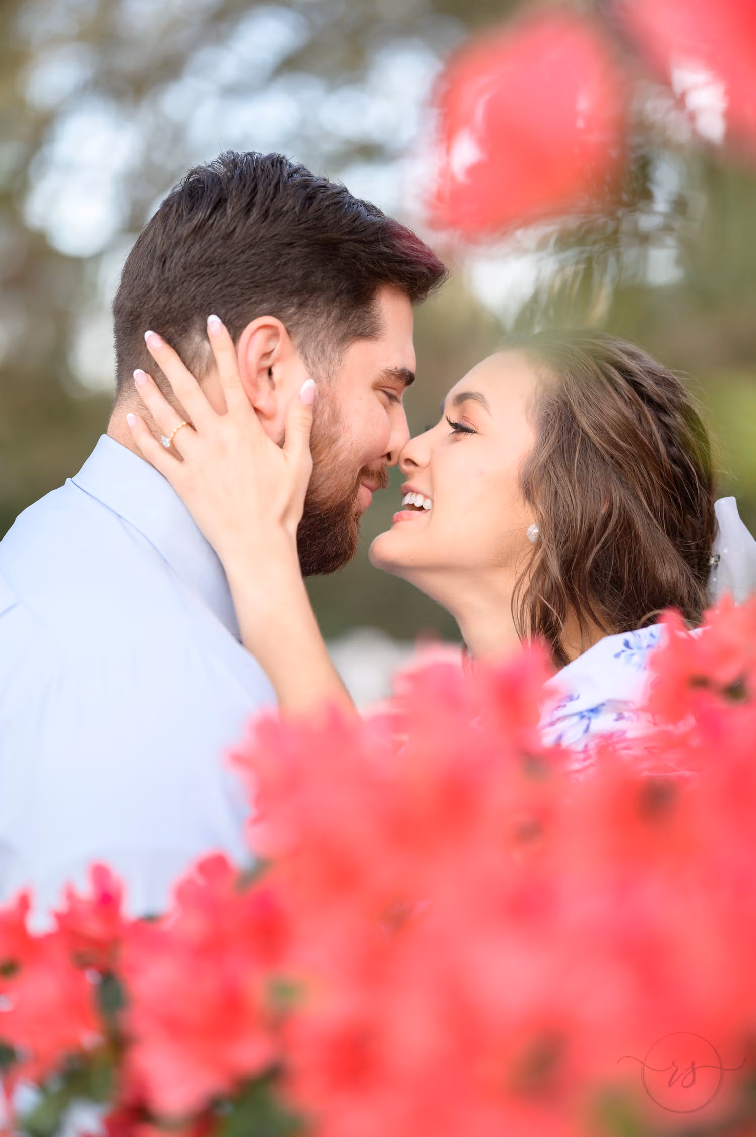 Couple touching noses with pink azalea blossoms in the foreground at Caledonia Golf and Fish Club