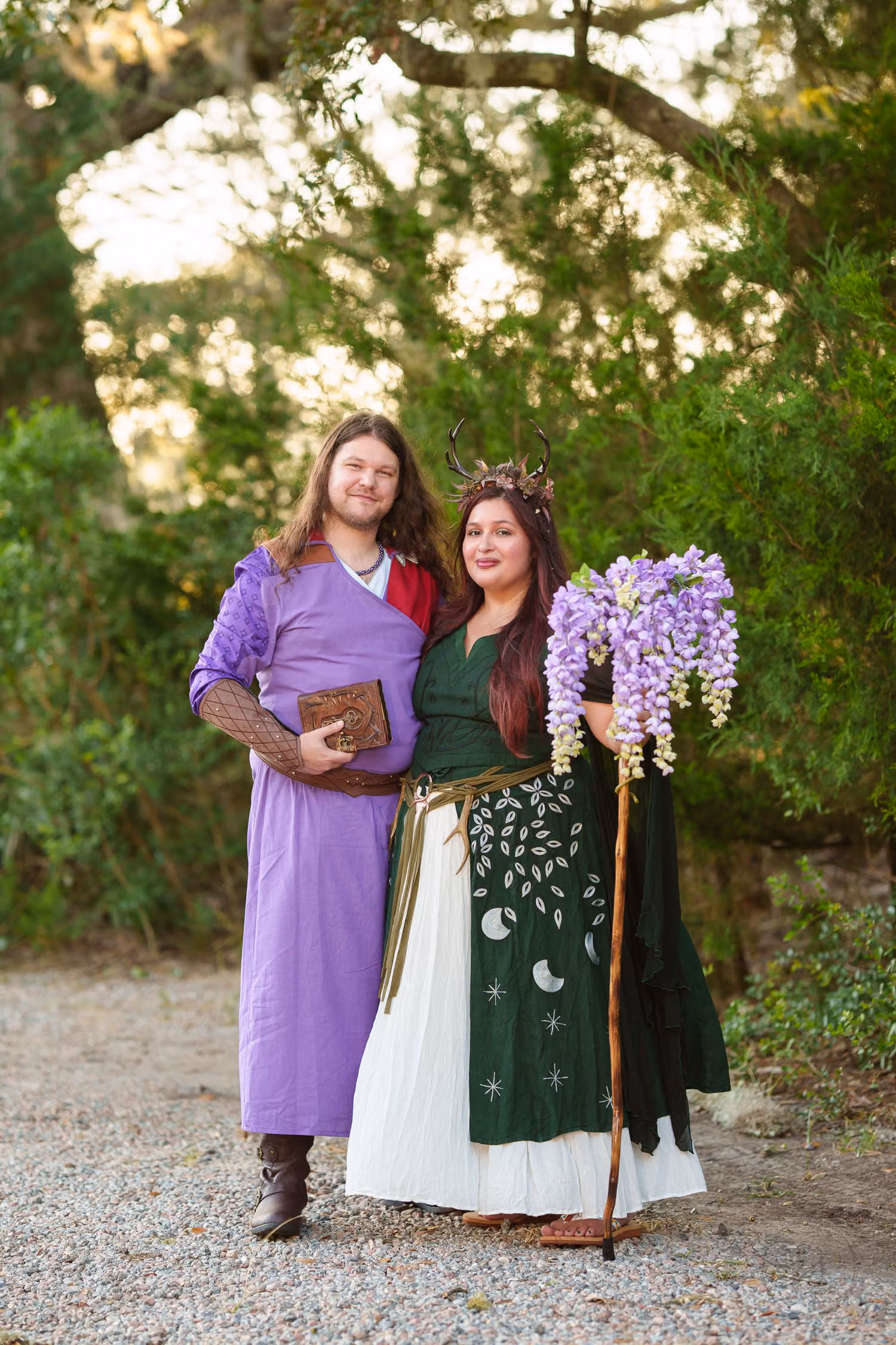 Couple in costume, he in a purple robe and she in a green gown with a flowered staff, at Huntington Beach State Park