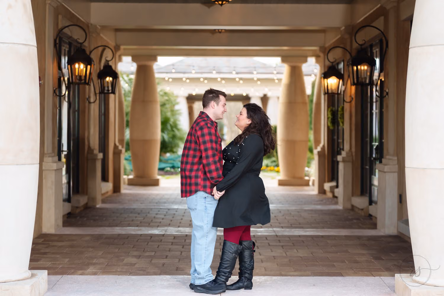 Couple standing close in a long covered portico lit by lanterns at 21 Main Events