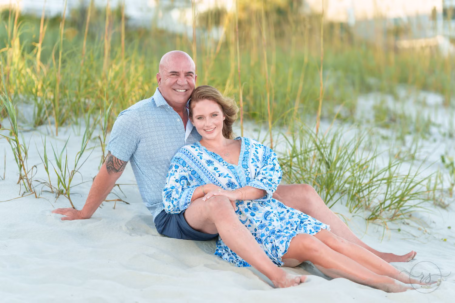 Couple relaxing side by side in the sand in front of the sea oats on Surfside Beach