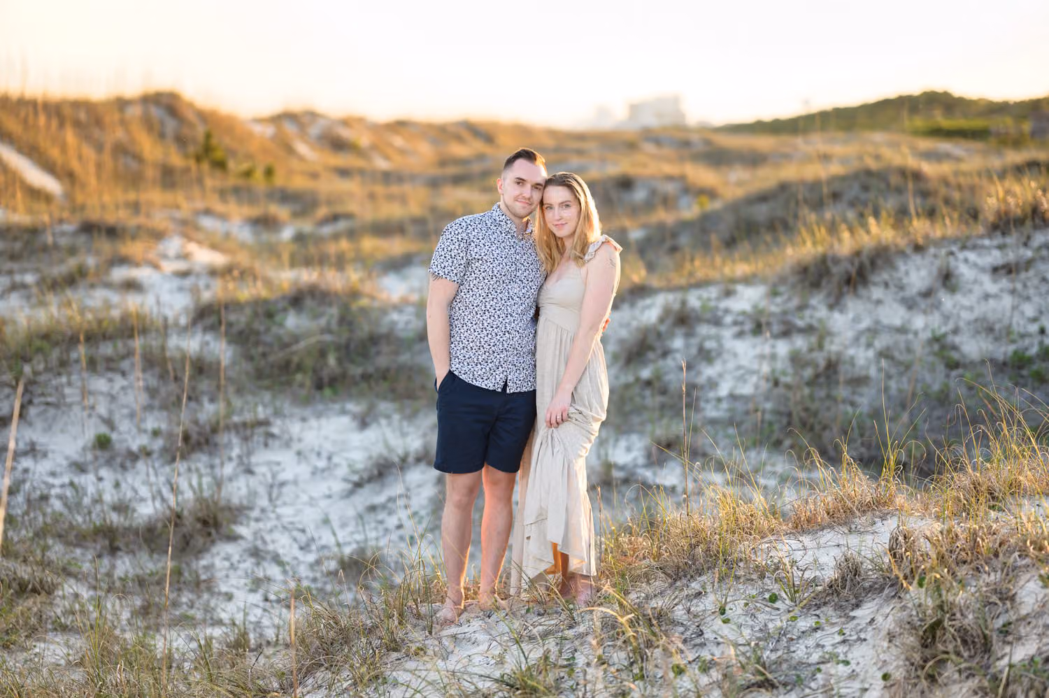 Couple standing close among the dune grass and sea oats in warm light at Inlet Point Plantation
