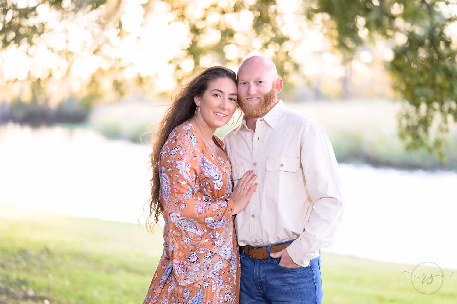 Couple leaning their heads together by the river in warm evening light at Caledonia Golf & Fish Club