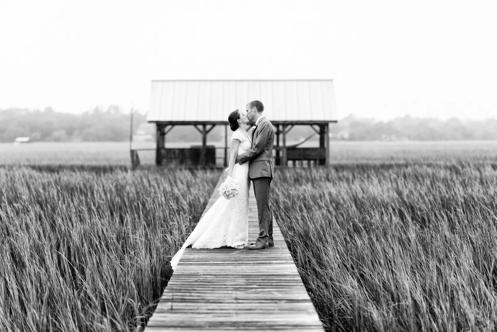 Couple kissing on a marsh walkway in black and white - The Pelican Inn