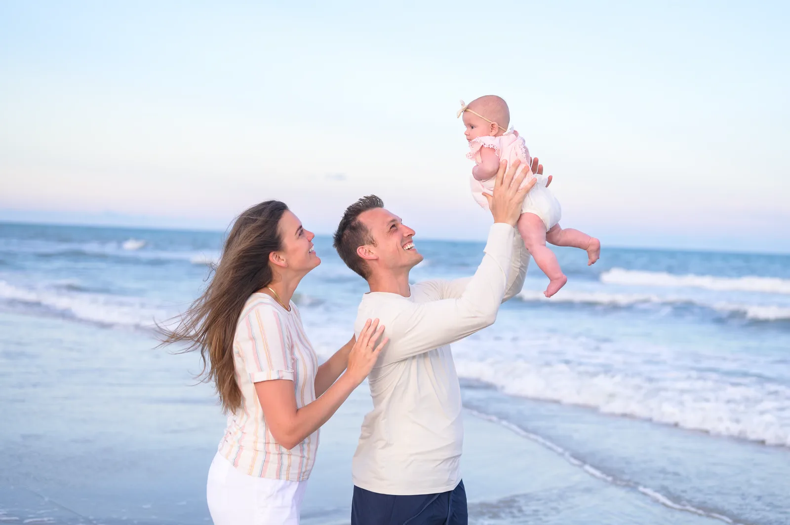 Mom and dad holding baby girl in the air - Huntington Beach State Park