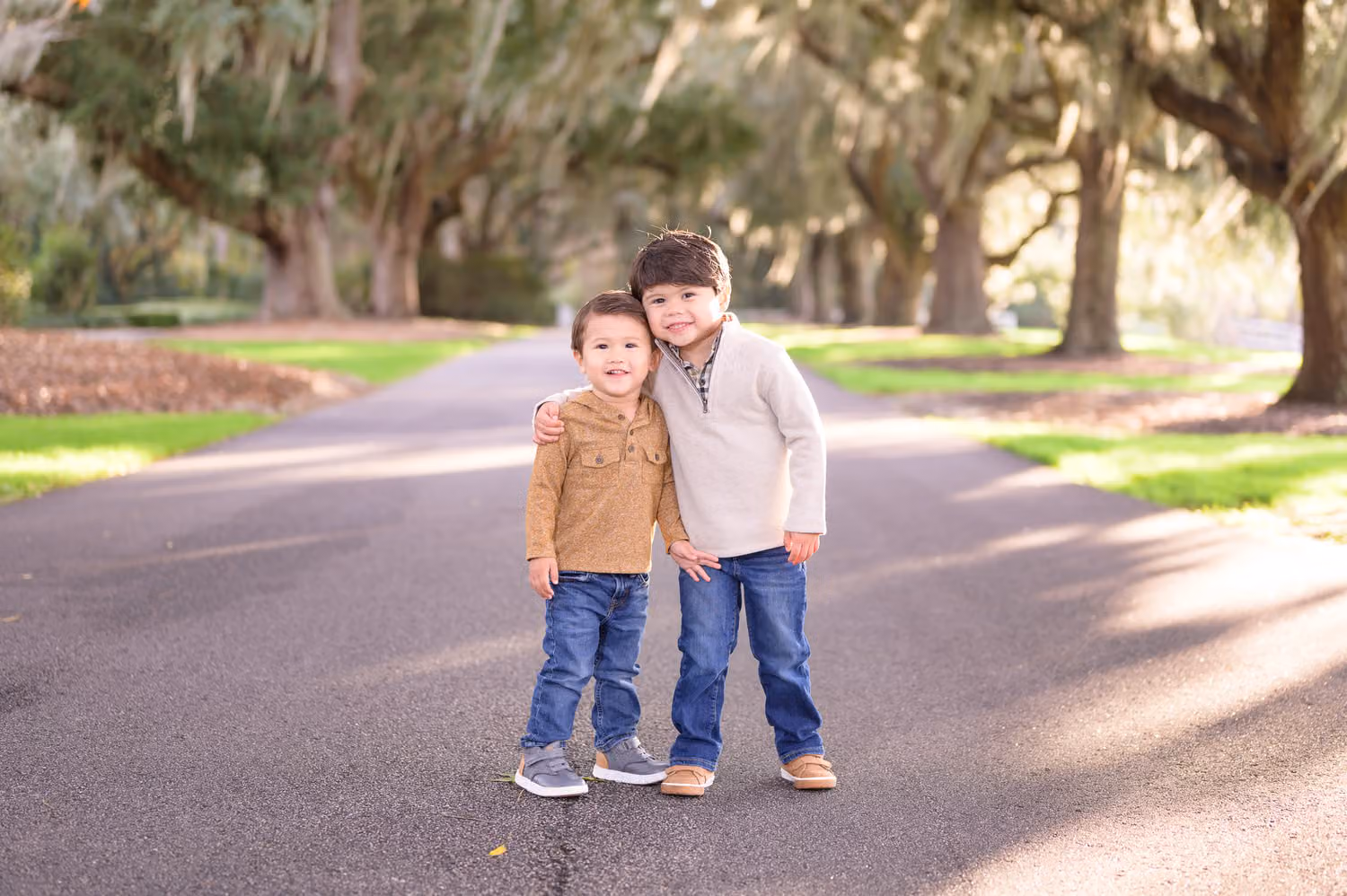 Two little brothers standing on the road beneath oaks draped in Spanish moss at Caledonia Golf & Fish Club