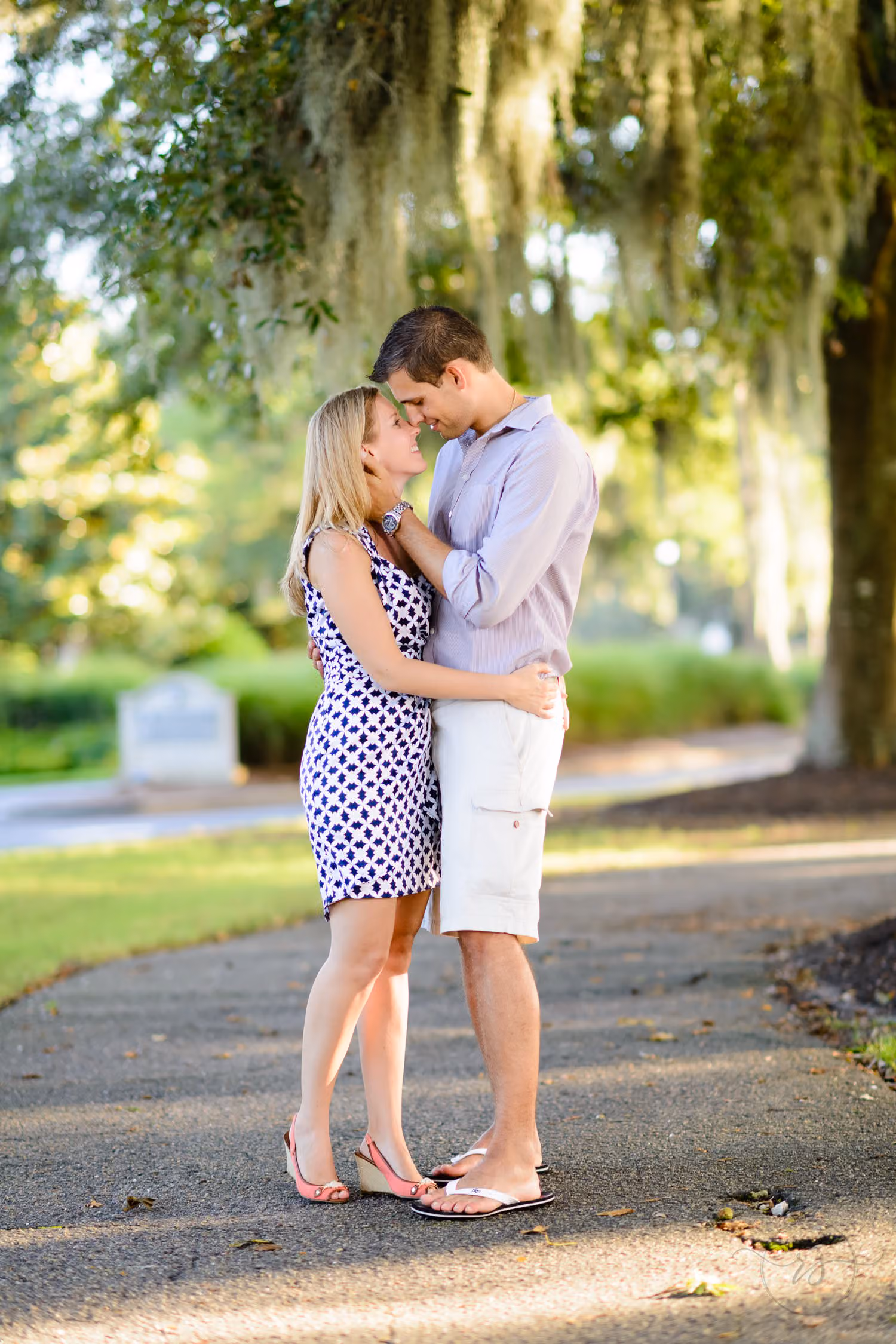 Couple standing close on a path beneath oak trees draped in Spanish moss in Litchfield