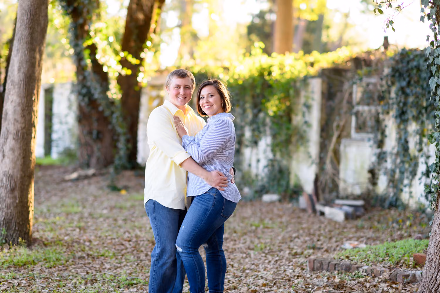 Smiling couple hugging under trees in front of an old ivy-covered building in Pawleys Island