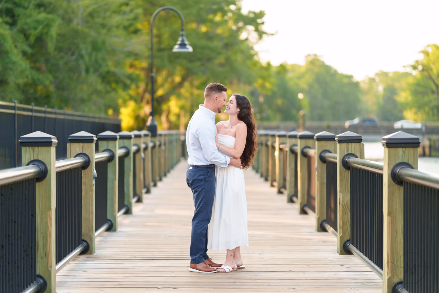 Couple standing close on the new section of the wooden boardwalk lined with lampposts at the Conway Riverwalk