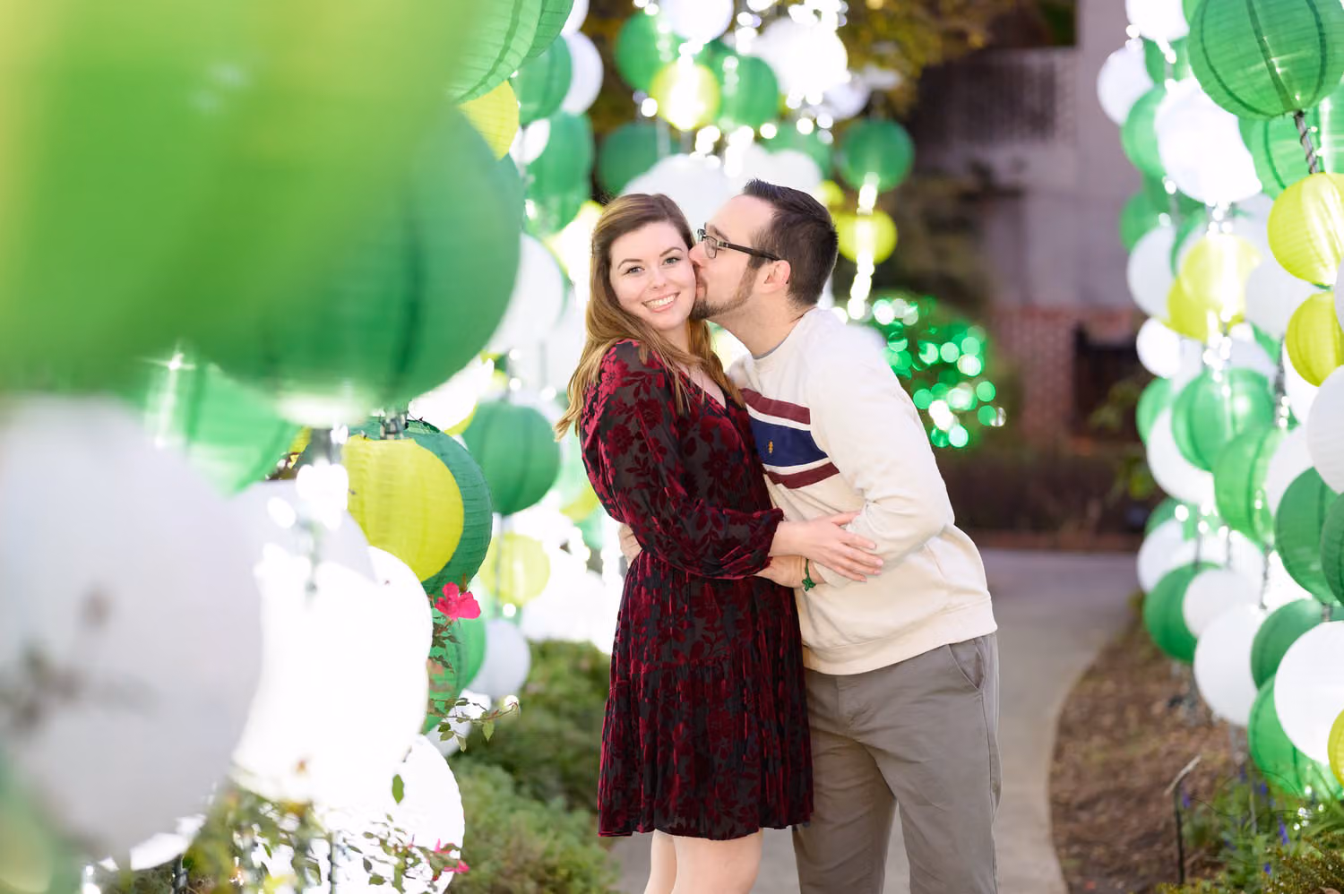 Couple cuddling between glowing green and white lanterns during Night of a Thousand Candles at Brookgreen Gardens