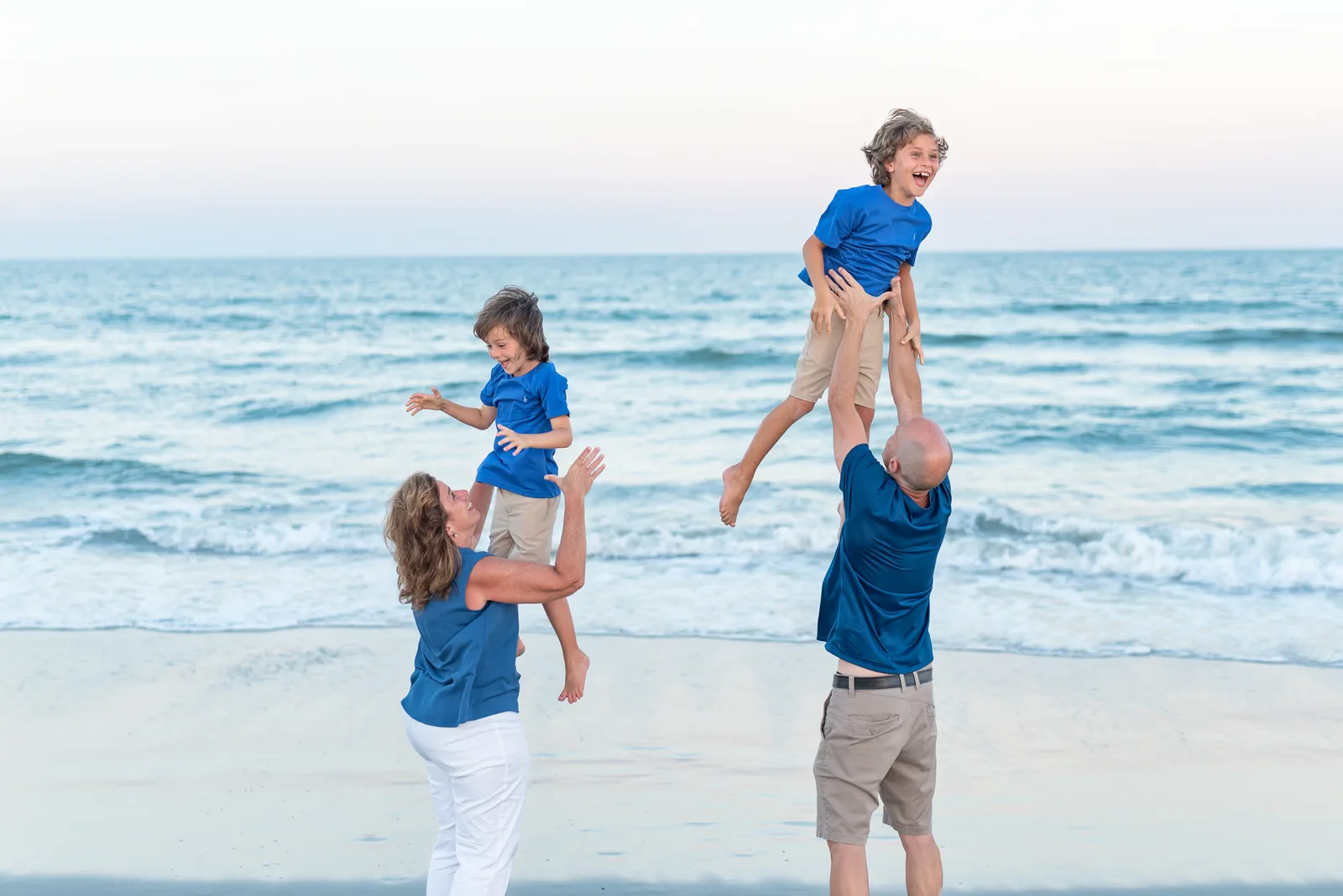 Mom and dad throwing sons into the air - Huntington Beach State Park
