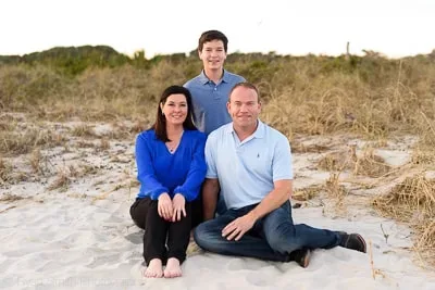 Family of 3 sitting in front of the dunes