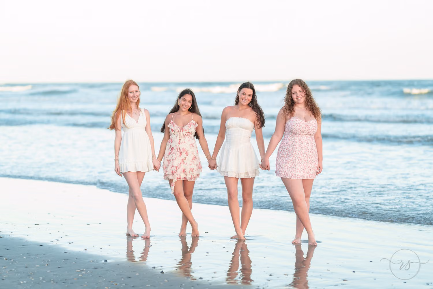 Four senior girls in sundresses walking hand in hand along the water's edge in North Myrtle Beach